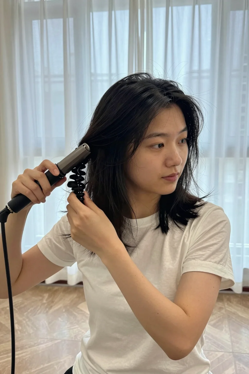 Adult woman with shoulder-length dark hair using a clamp curling iron.
